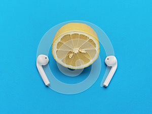 Half a lemon with wireless headphones on a blue background