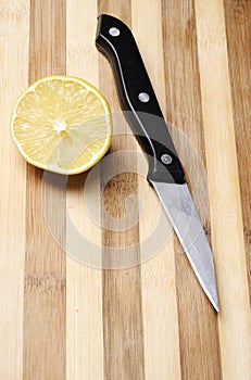 Half of lemon on wood kitchen board and knife