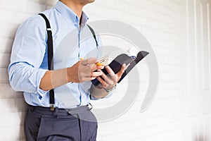 Half-length,Close up Man in blue shirt holding black book of the Bible, Buddhist, Catholic, Christian, prayer,on wall background