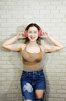 Half length portrait asian woman smile happily and enjoy listening to music,wearing red headphones,wearing brown vest with denim