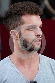 Half-length portrait of a boy with a gray t-shirt with a beard, semi open mouth.