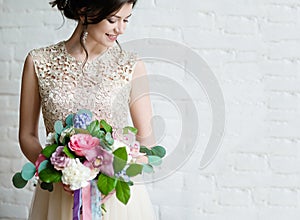 Half length portrait of brunette smiling woman dressed in sleeveless light evening dress