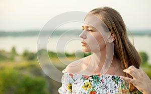 Half length portrait of charming positive woman is looking epically off into the distance in sunset background