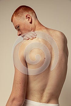 Half-length portrait of muscular male back isolated over grey studio background. Model posing in underwear. Body art