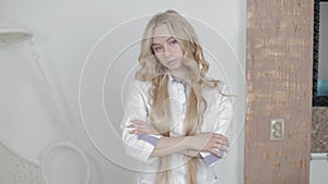 Half-length portrait of pretty young blond Caucasian woman doctor cosmetologist beautician, posing to camera indoor in