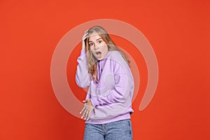 Half-length portrait of scared and shocked young girl isolated on red studio background. Concept of human emotions