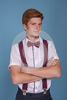 Half length  portrait of a  stylish red-haired young smiling man with arms crossed against  blue background in the studio