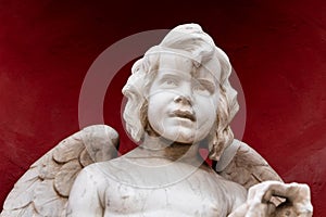 Half-length portrait of a winged cherub on a red background.