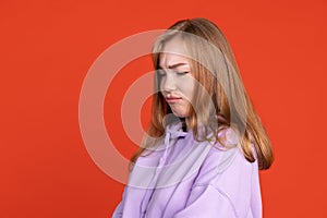 Half-length portrait of young girl pouting her lips isolated on red studio background. Concept of human emotions