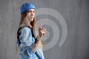 Half-length portrait of a young pretty long-haired girl in a blue sweater and cap with DJ headphones on her shoulder