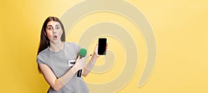 Half-length portrait of young shocked girl, correspondent using phone isolated on yellow studio background. Concept of