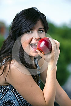 Half-length portrait of young woman eating red apple