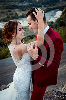 Half-length sensitive wedding portrait of the hugging couple. The charming smiling bride is stroking the hair of the