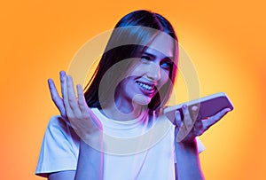 Half-length shot of emotional girl with long glossy dark hair isolated on orange background in neon light. Concept of