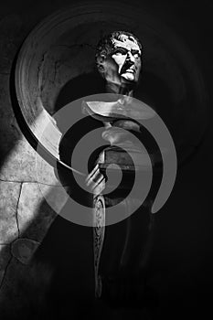 Half-length statue portrait black and white vertical background in the dark with sunrays filter through shadows.