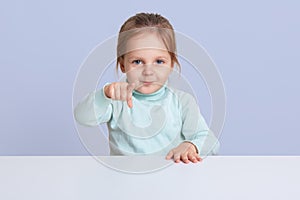 Half length studio photo of charming little girl wearing casually, pointing directly at camera, showing something to her mother,