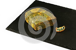 Half a loaf of mouldy rye bread and a piece of kiwi with a mold on a black shale board isolated on white background, concept of in