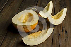 Half a melon and a few pieces are cut into slices. ON the table is a melon without seeds cut.