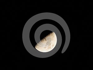 Half Moon in the Winter Night Sky: A luminous half moon with details of craters and dark and light spots on a cold winter night