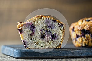 Half muffin with blueberries and walnuts on wooden table, closeup. Sweet pastries on the board. Fresh cupcakes for breakfast