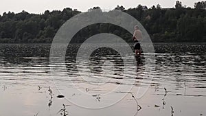 Half-naked fisherman with a fishing rod fishing in the calm river