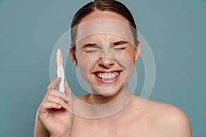 Half-naked ginger woman smiling and showing pregnancy test