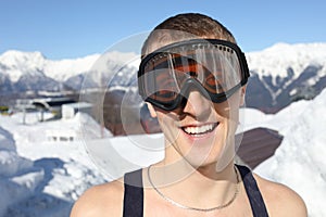 Half-naked skier in ski goggles smiles on mountain photo