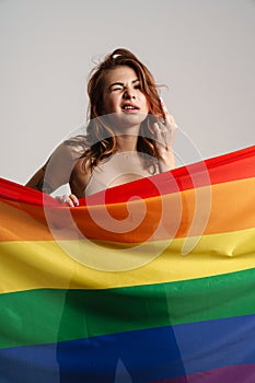 Half-naked woman showing middle finger while posing behind rainbow flag