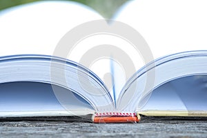 Half open book on wooden table with nature background