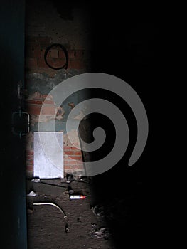 A half-open door to an abandoned room on a dirty floor lighting penetrates photo