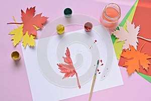 Half-painted maple leaf, paint and brush. Unfinished work. Quitter. Pass of difficulties. Autumn melancholy