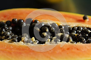 Half a papaya fruit, close up of black papaya seed