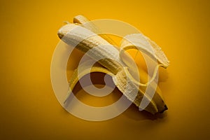 Half-peeled banana on the yellow background