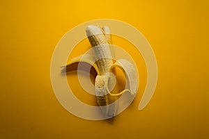 Half-peeled banana on the yellow background