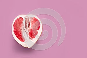 A half peeled grapefruit on a pink colored background. Minimal still life