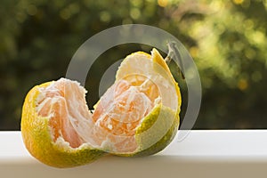 Half peeled tangerine on garden table