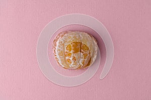 Half a peeled tangerine on a pink-pastel background.