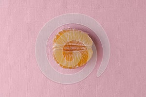 Half a peeled tangerine on a pink-pastel background.