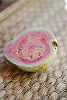 Half of pink guava on a rattan mat.