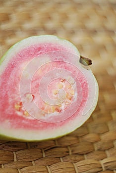 Half of pink guava on a rattan mat.
