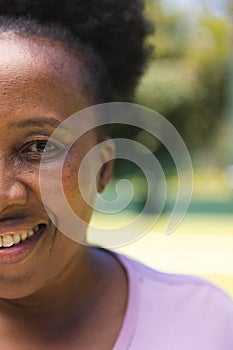 Half portrait of happy senior african american woman at sunny grass tennis court