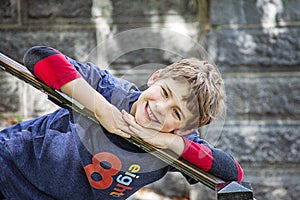 Half portrait of happy eight year old birthday boy wearing number 8 shirt leaning on stair rail