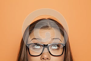 Half portrait of a young girl with glasses looking up