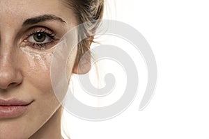 Half portrait of a young woman posing with concealer under her eyes on white background