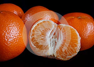 Half purified mandarine and whole tangerines. black background