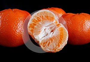 Half purified tangerine and whole tangerines. black background