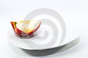 Half red apple with a missing bite on a white plate