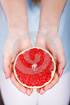 Half of red grapefruit citrus fruit in human hands