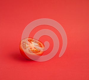Half of a red ripe tomato on a red background