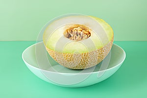 half ripe Galia melon with the seeds inside on a blue deep plate